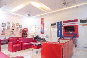 uma sala de estar com mobiliário vermelho e uma televisão em Londres Bed and Breakfast RedPartner near Gembira Loka Zoo em Yogyakarta