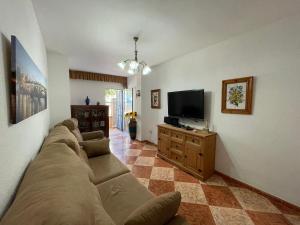 ein Wohnzimmer mit einem Sofa und einem Flachbild-TV in der Unterkunft Espectacular apartamento junto al mar in Chipiona