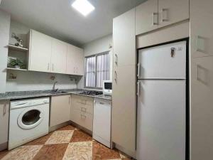 uma cozinha com armários brancos e um frigorífico branco em Espectacular apartamento junto al mar em Chipiona