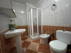 uma casa de banho com um chuveiro, um WC e um lavatório. em Espectacular apartamento junto al mar em Chipiona