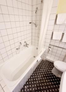 a white bathroom with a tub and a toilet at Hotel Heikenberg in Bad Lauterberg