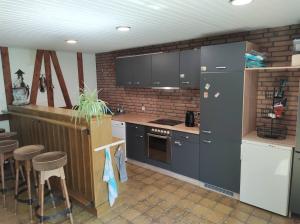 eine Küche mit grauen Schränken und eine Bar mit Hockern in der Unterkunft Five Oaks Hamburg in Hamburg
