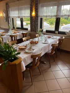 a table in a restaurant with white tables and chairs at Gasthaus Hubertus in Reuth