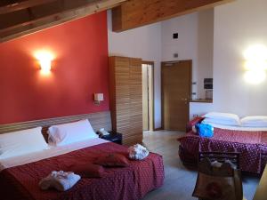 a bedroom with two beds and a red wall at Albergo Cavallino Bianco in Rumo