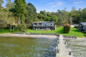 a house on the shore of a river with a dock at Onepoto Bay Lakehouse - Lake Rotoiti Holiday Home in Okere Falls