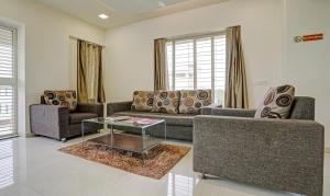 a living room with two couches and a glass table at Treebo Trend Excellent Homes, Nashik in Nashik