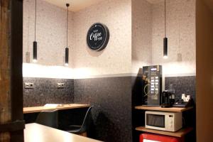 cocina con microondas y reloj en la pared en Woohoo Rooms Chueca en Madrid