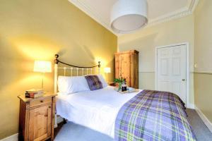 a bedroom with a large bed with a plaid blanket at ALTIDO Lovely 1 bed flat in Old town, right on the Royal Mile in Edinburgh