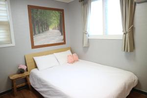 Un dormitorio con una cama blanca con una foto en la pared en Rain Boots Guest House, en Incheon