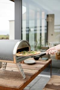 una persona está sacando una pizza de un horno en Gate Lodge@White Strand, en Miltown Malbay