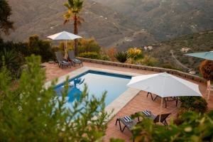 a swimming pool with umbrellas and chairs next to a mountain at Casa Admar in Sayalonga