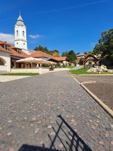 a cobblestone street in front of a church with a tower at Tarcal Apartman in Tarcal