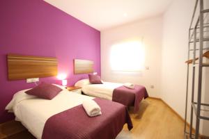 a hotel room with two beds and purple walls at Apartamentos Tito San Agustin in Alicante