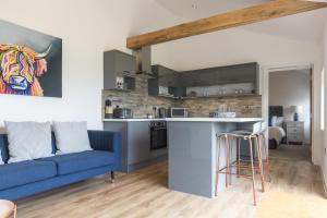 a living room with a blue couch and a kitchen at Apartment in the Countryside with Hot Tub in Trowbridge +11 photos