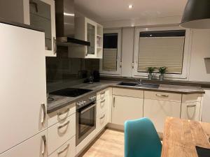 een keuken met witte kasten en een blauwe stoel bij Lieblingsplatz-Winterberg in Winterberg