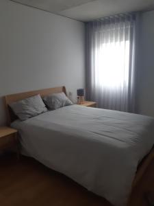 a bedroom with a large white bed with a window at Apartamento T3 junto à ria e ao mar! in Gafanha da Nazaré