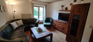 ein Wohnzimmer mit einem Sofa und einem TV in der Unterkunft Ferienwohnung Haus Alpenrebe in Schönau am Königssee