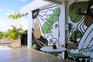 a patio with a table and chairs in front of a mural at Ananzitra Hotel in Kanchanaburi City