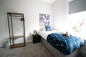 1 dormitorio con 1 cama con manta azul y ventana en Ideal Lodgings in Royton, en Royton