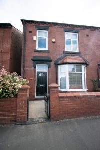 a red brick house with a black door at Ideal Lodgings in Royton in Royton