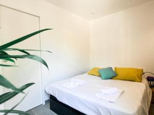 a bedroom with a bed with yellow and green pillows at KORALA T2 Marne ville & plage in Biarritz