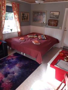 a bedroom with a red bed and a rug at Cosy non smoking Cabin close to beach,Alnö in Sundsvall