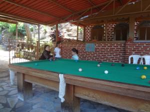 two girls playing a game of pool in a pool table at Pousada do Bezerra in Caparaó Velho