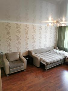 ein Schlafzimmer mit einem Bett, einem Sofa und einem Stuhl in der Unterkunft 1 комн квартира в центре in Qostanai