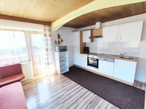 a kitchen with white cabinets and a wooden floor at Chalet in Hippach near Ski Paradise in Hippach +28 photos