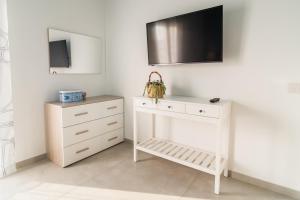 een witte dressoir met een televisie aan de muur bij Pilar Apartment Vista Mare in Portopalo