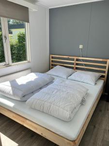 łóżko z białą pościelą i poduszkami w sypialni w obiekcie Holiday Chalet Basic w mieście Hensbroek