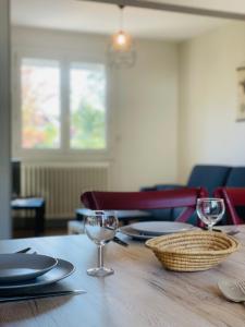 una mesa de madera con platos y copas de vino. en La Marnière - Magnificent house with garden in Chambray-lès-Tours, en Chambray-lès-Tours