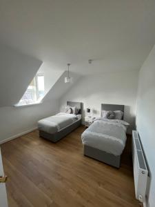 ein weißes Schlafzimmer mit 2 Betten und einer Treppe in der Unterkunft 57 Main Street Newcastle Luxury Central Apartment in Newcastle