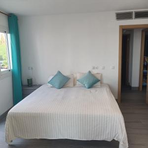 a bedroom with a large white bed with blue pillows at Duquesa Harbour Club Aparthotel in Manilva