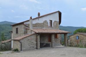 una vista esterna di una casa in pietra con montagne sullo sfondo di Casa vacanze Colle Bidoni a Santa Cristina