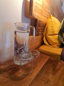a glass jug and two glasses on a wooden table at Fish eagle Guest Farm in Phalaborwa