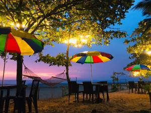 - une table et des chaises avec des parasols sur une plage dans l'établissement Alleppey Palm Beach Resort & Cafe, à Alappuzha