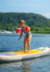 a young girl standing on a paddle board in the water at Camping Lido Verbano in Castelletto sopra Ticino