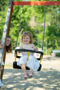 a little girl sitting on a swing at a park at Camping Lido Verbano in Castelletto sopra Ticino