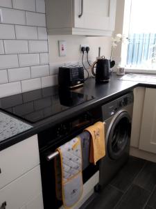 a kitchen with a stove with a washing machine at Fishermans Cottage in Killough