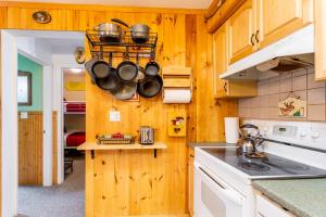 cocina con paredes de madera, fogones, ollas y sartenes en Mountainside Haven - walk to Hunter Mtn!, en Hunter