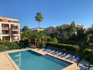 ein Swimmingpool mit Liegestühlen und Palmen in der Unterkunft Port Marine in Sainte-Maxime