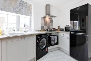 uma cozinha com uma máquina de lavar roupa e um lavatório em 3-bed in Mumbles with free parking & sea views em The Mumbles