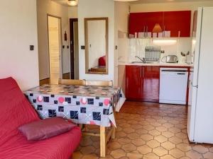 uma cozinha com uma mesa e um sofá vermelho em Appartement Bormes-les-Mimosas, 2 pièces, 4 personnes - FR-1-610-16 em Bormes-les-Mimosas