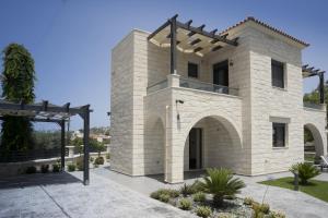 una casa de piedra con un arco en un patio en Villa-Azalea, en Almyrida