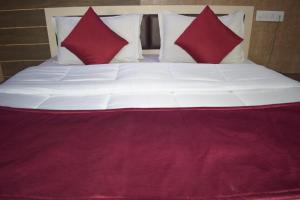uma cama grande com duas almofadas vermelhas em The Sky Comfort - Hotel The Heaven, Dwarka em Dwarka