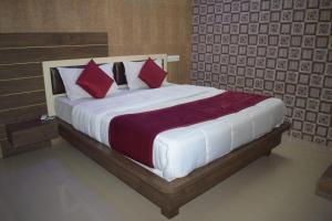 um quarto com uma cama grande e almofadas vermelhas em The Sky Comfort - Hotel The Heaven, Dwarka em Dwarka