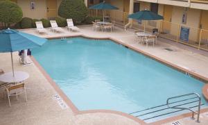 una gran piscina con mesas, sillas y sombrillas en Baymont by Wyndham Abilene, en Abilene