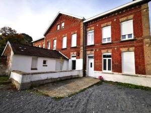 an old brick building with a parking lot in front of it at La Maison Jaurès - La Trappiste in Liévin