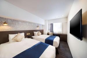 横浜市にあるベストウェスタンホテルフィーノ新横浜のベッド2台、薄型テレビが備わるホテルルームです。
